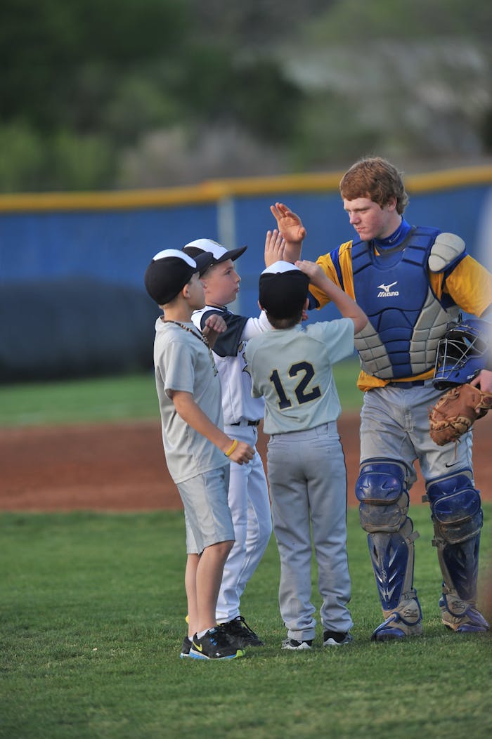 why-choose-us Young baseball players celebrate sportsmanship with a high-five on the field.