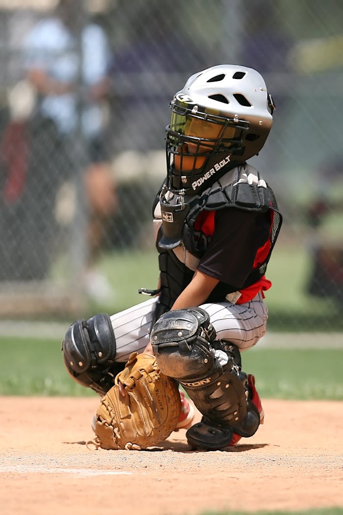 gallery-5 A young baseball catcher in full gear crouches on the field, ready for action.