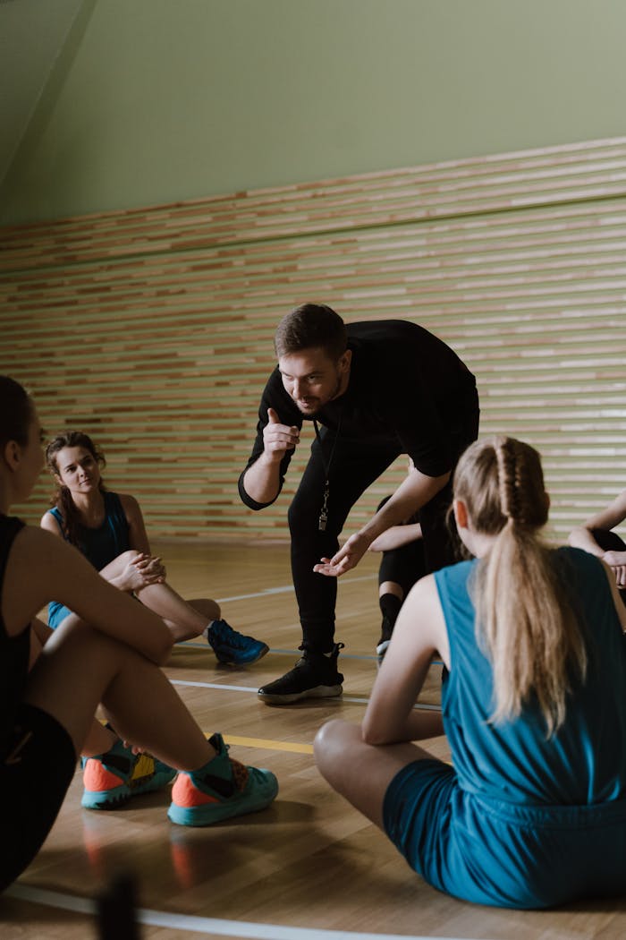 gallery-3 A group of female basketball players receiving guidance from a coach indoors.